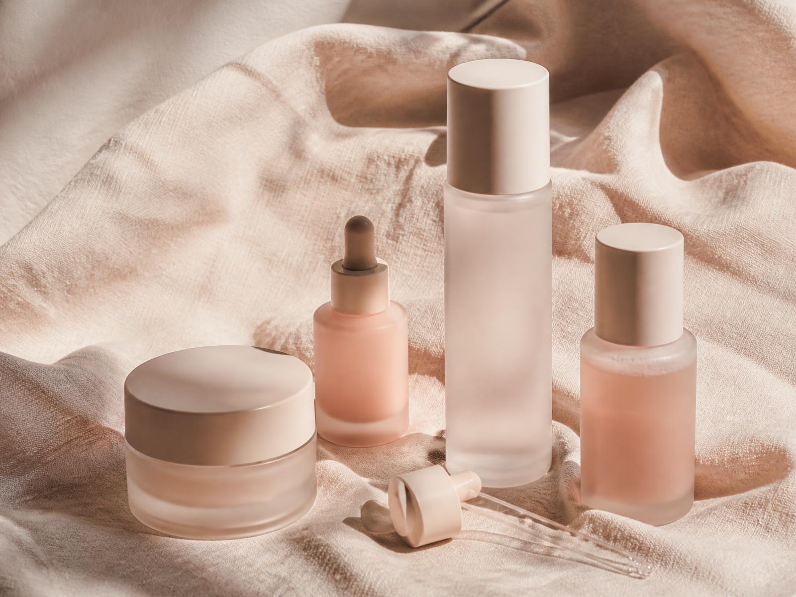 Unbranded skincare bottles arranged on cream linen
